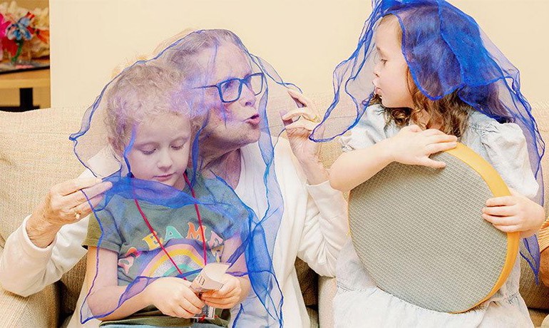 Adult Day Club participant playing with two young children