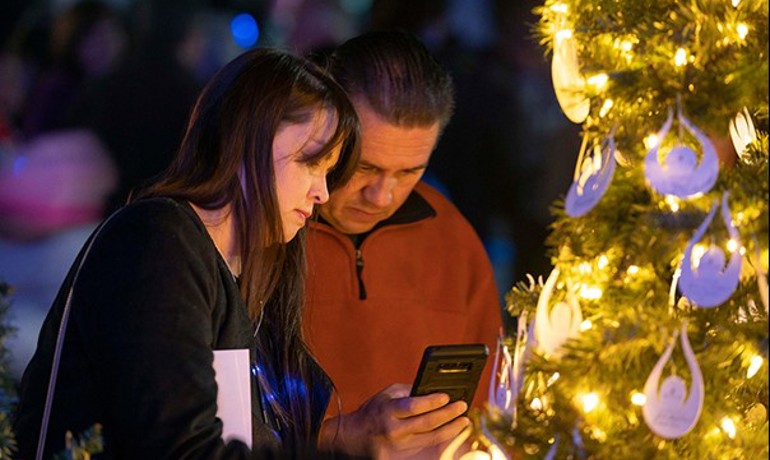 Two attendees look at a photo together near a Christmas tree