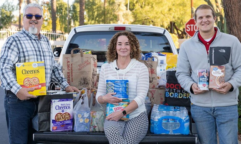 Joe Campaigne and Jace Orcutt pose with Maggie Martel and donated food items.