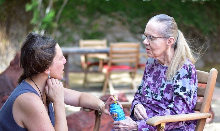 Woman kneeling and talking to older woman in rocking chair