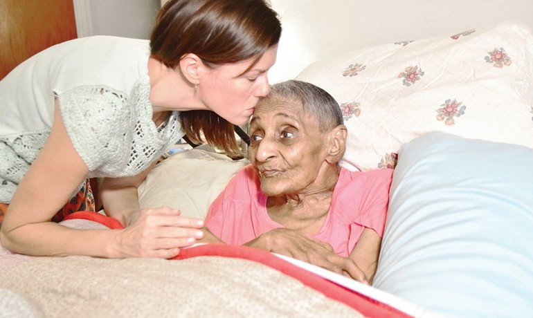 Social worker Erin Butler kisses patient Tressie Jennings on the forehead.