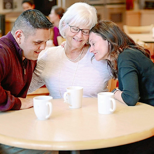 Three people comforting each other during grief support session