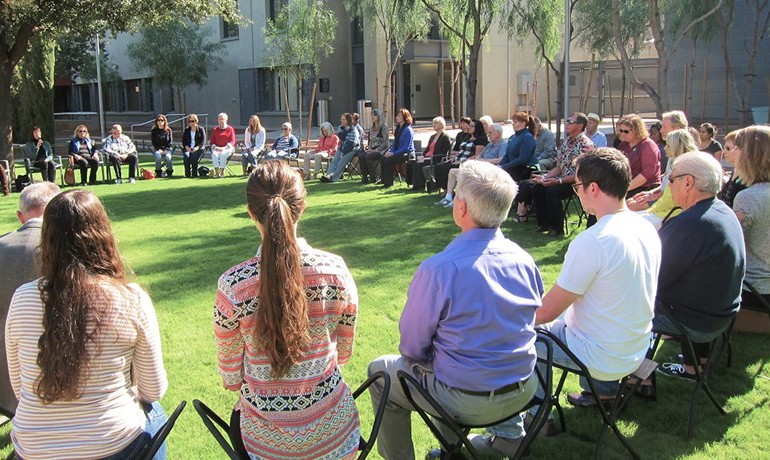 People seated in large circle outside practicing mindfulness 