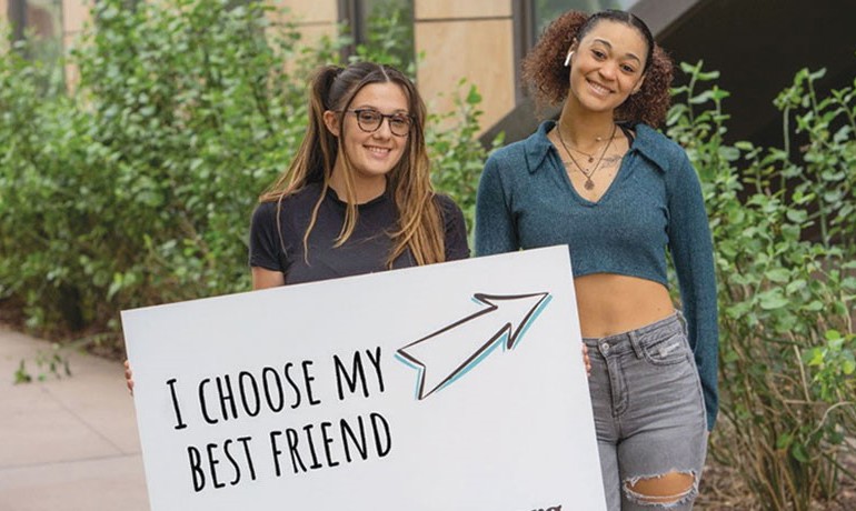 Two women posing together with sign saying, "I choose my best friend."
